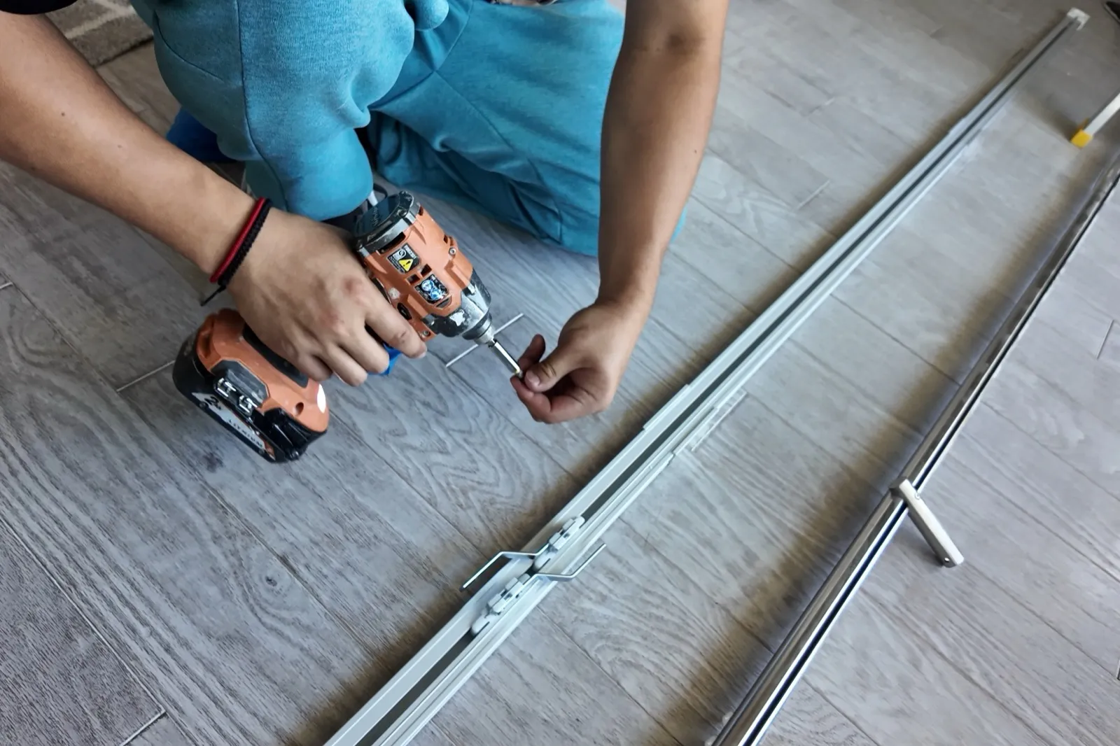 Installer fastening motorized curtain track hardware on the floor